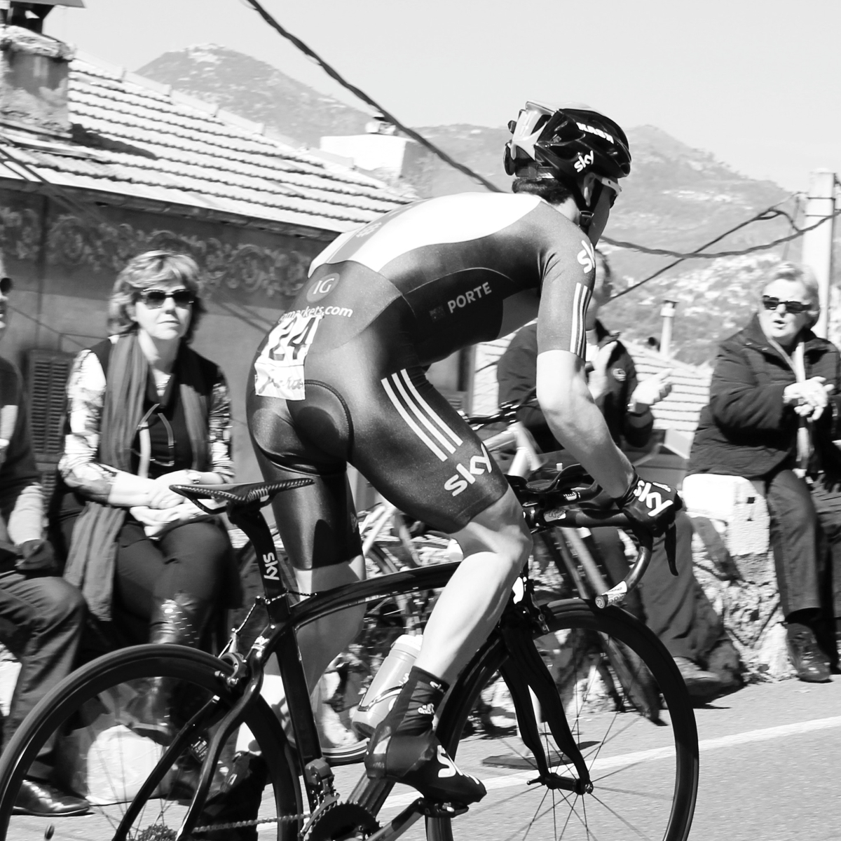 A racing cyclist on his bike passing a few spectators.