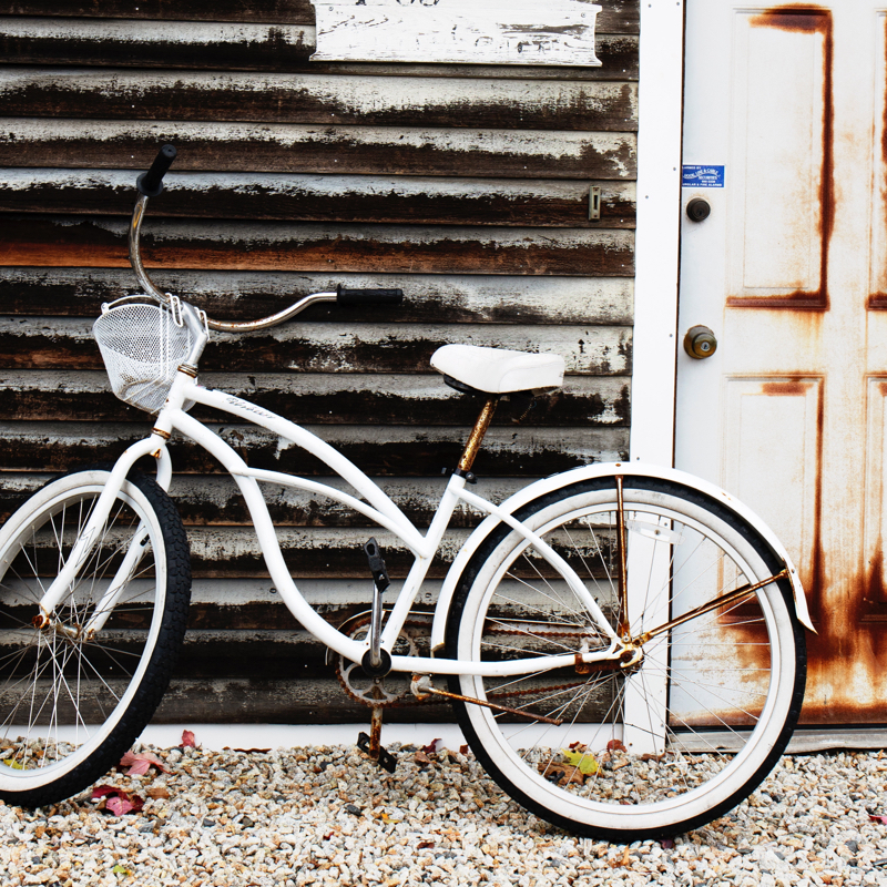 A coaster bike resting against a building.